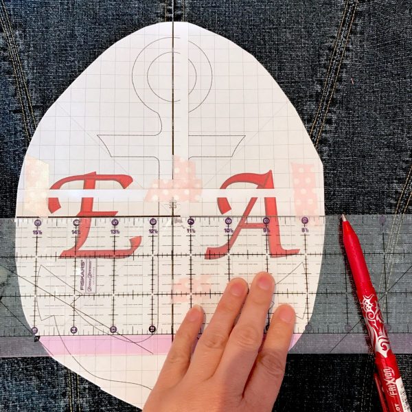 Decide where you would like the design to fall horizontally on your jacket, and slide the template up, or down, in place. Layer a ruler across the horizontal center line on the template, and mark the horizontal line onto the jacket. Remove the template and connect the two horizontal marks on your jacket back.