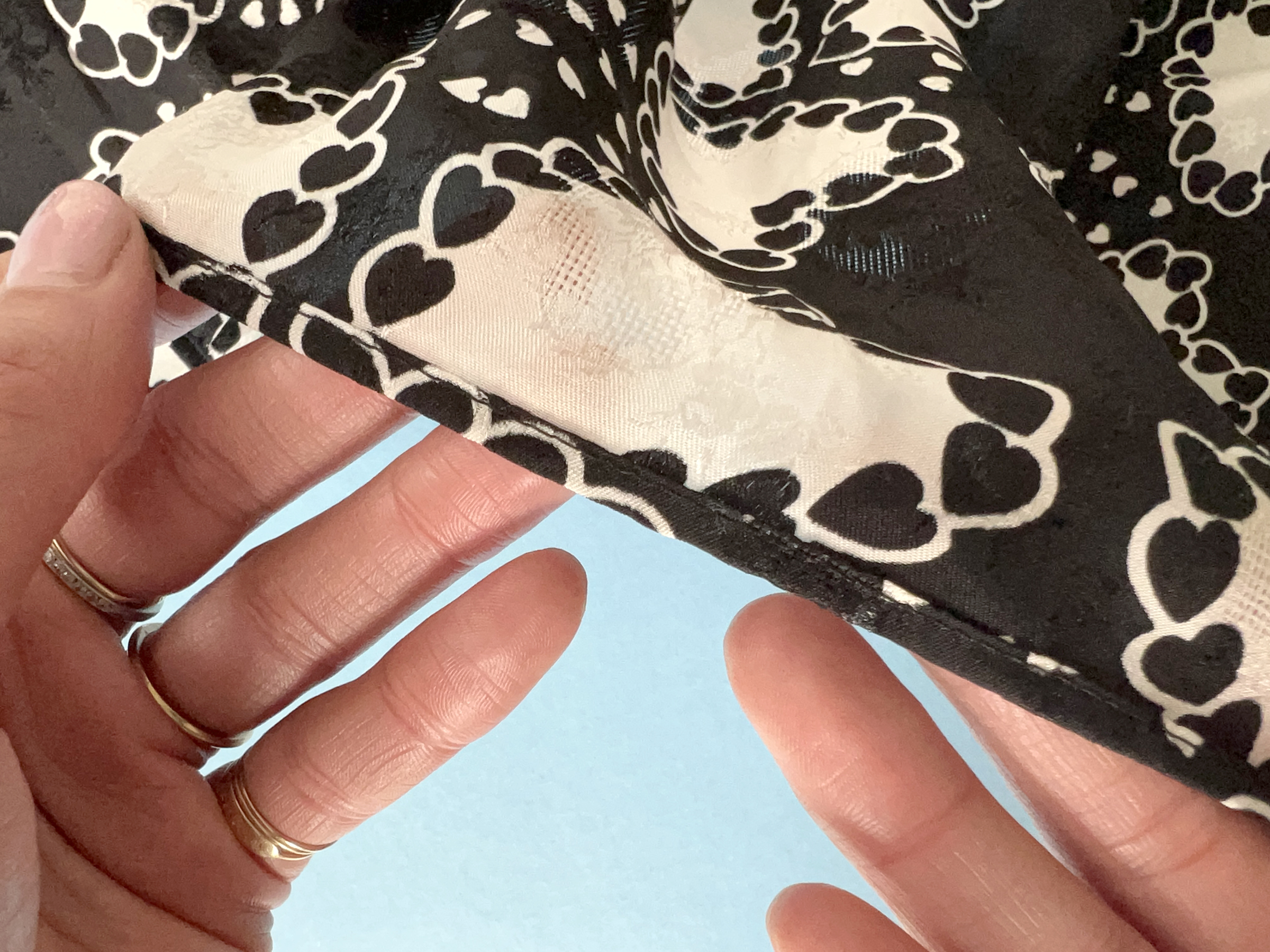 A close up of black and white fabric with a small, machine sewn rolled hem.