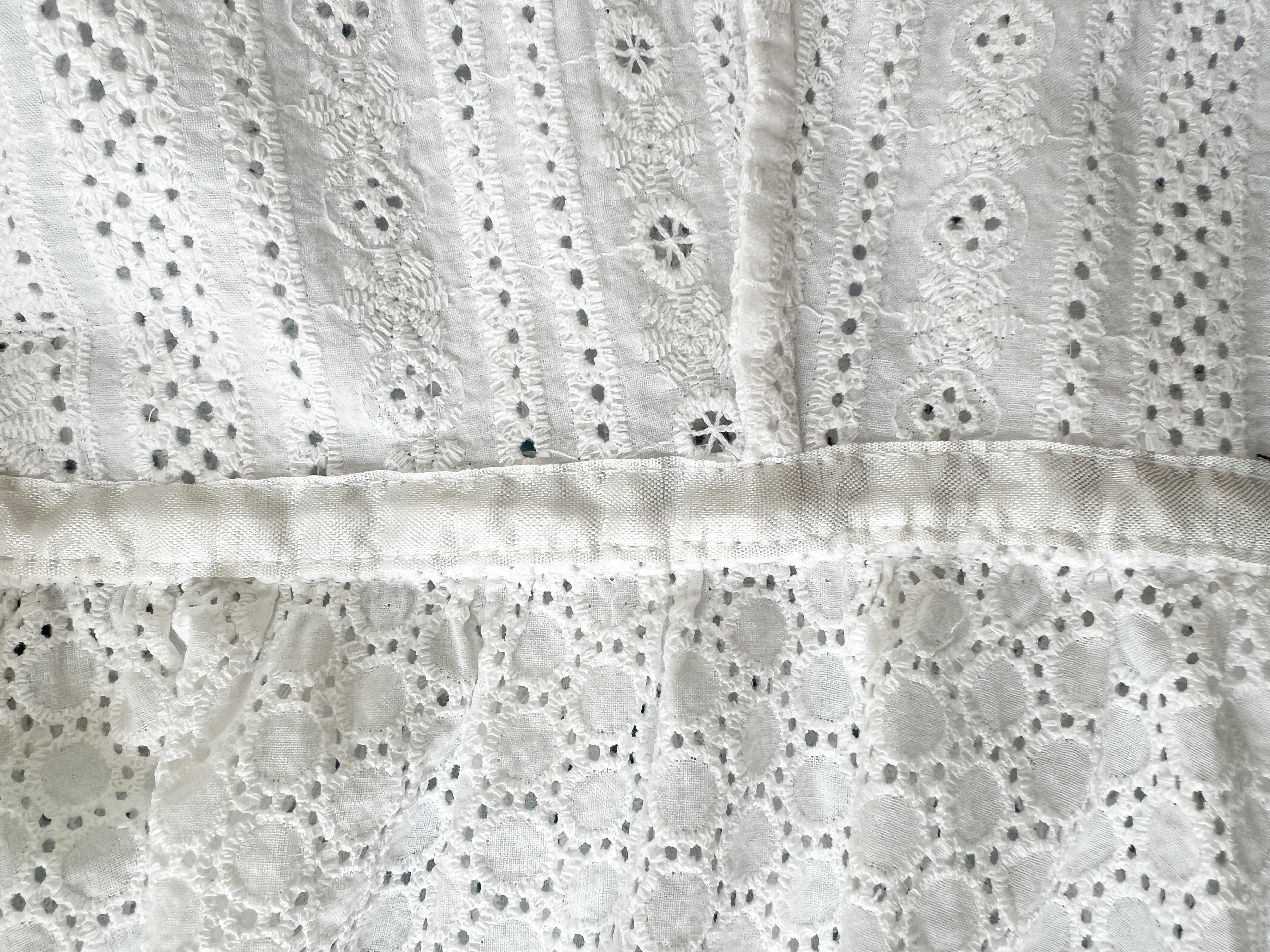 Seam finishes on the inside of a white eyelet dress, including a French Seam meeting a seam covered with rayon seam binding.