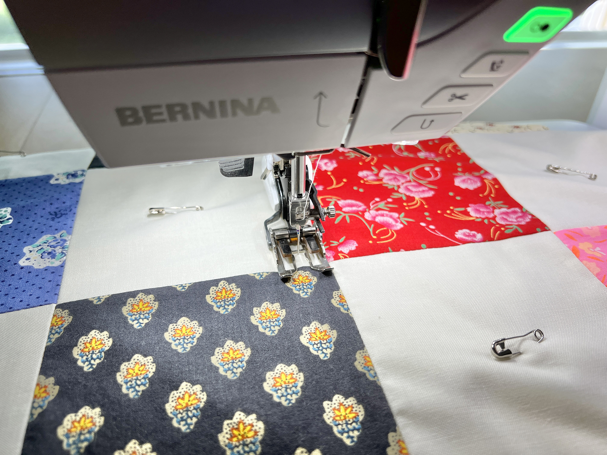 A BERNINA sewing machine with a walking foot is sewing through a quilt.