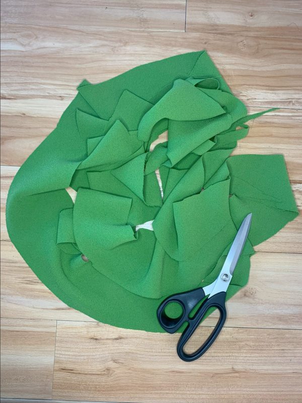 Green fabric trimmed from skirt hem and scissors