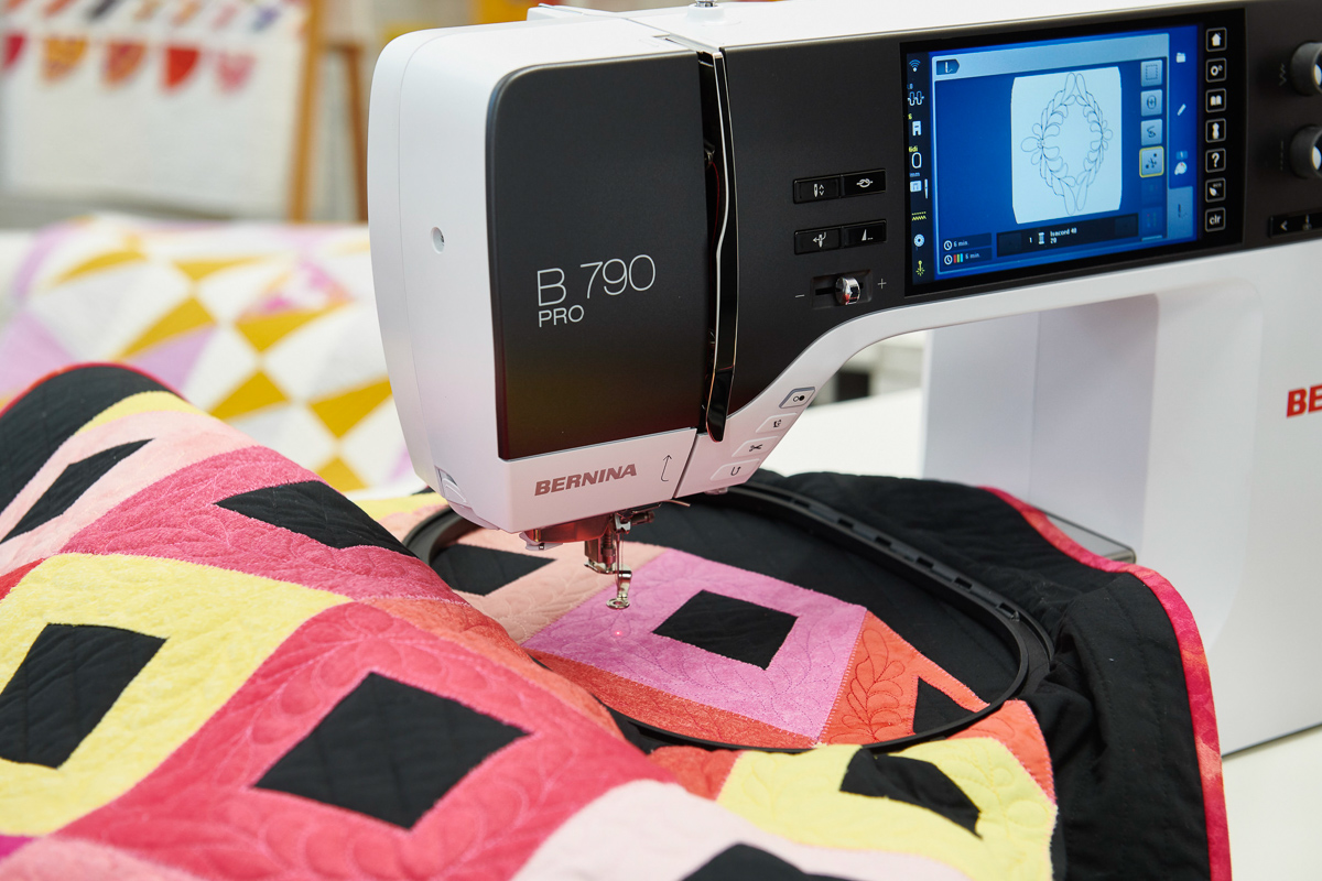 quilting through a hoop onto a red, orange, and yellow quilt using the B 790 PRO