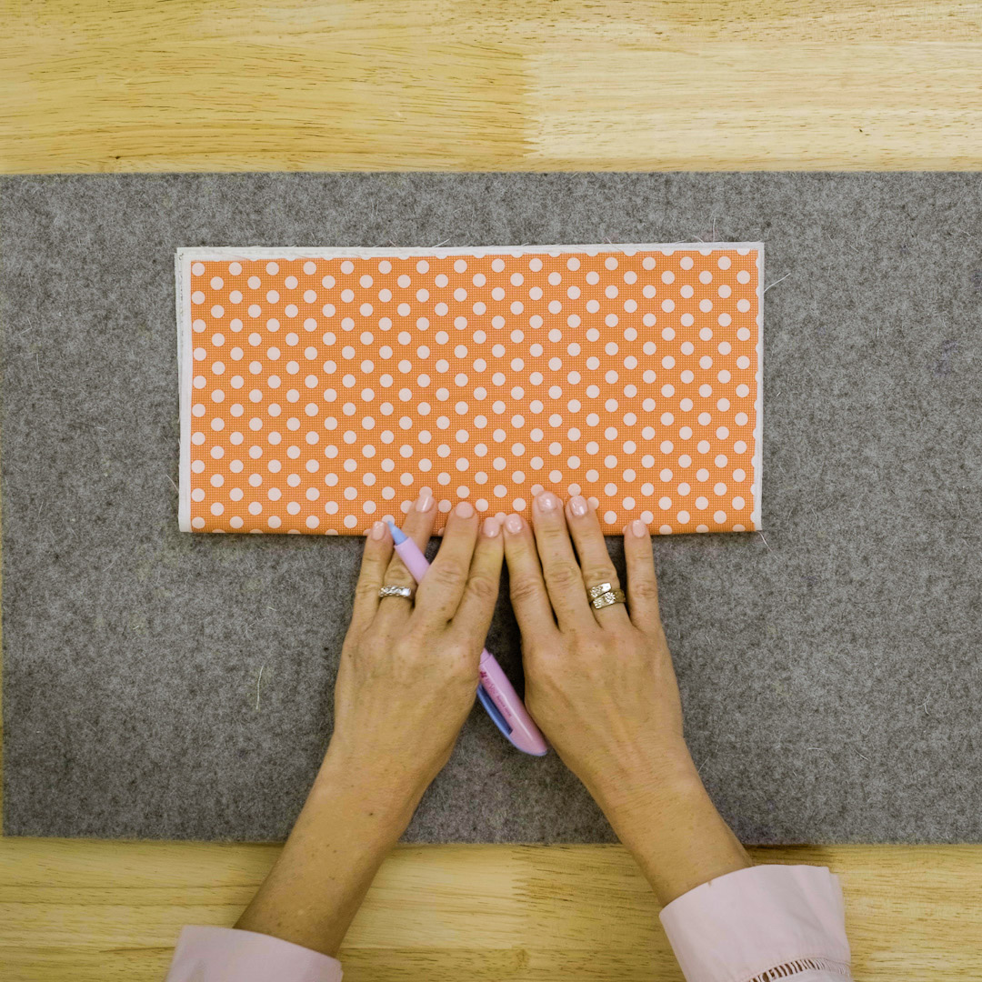 orange polka dot fabric being folded in half lengthwise