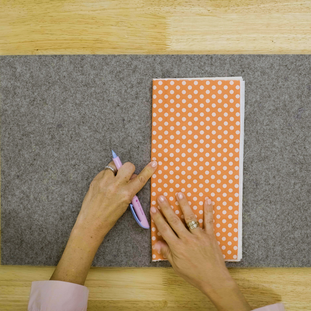orange polka dot fabric being folded in half widthwise