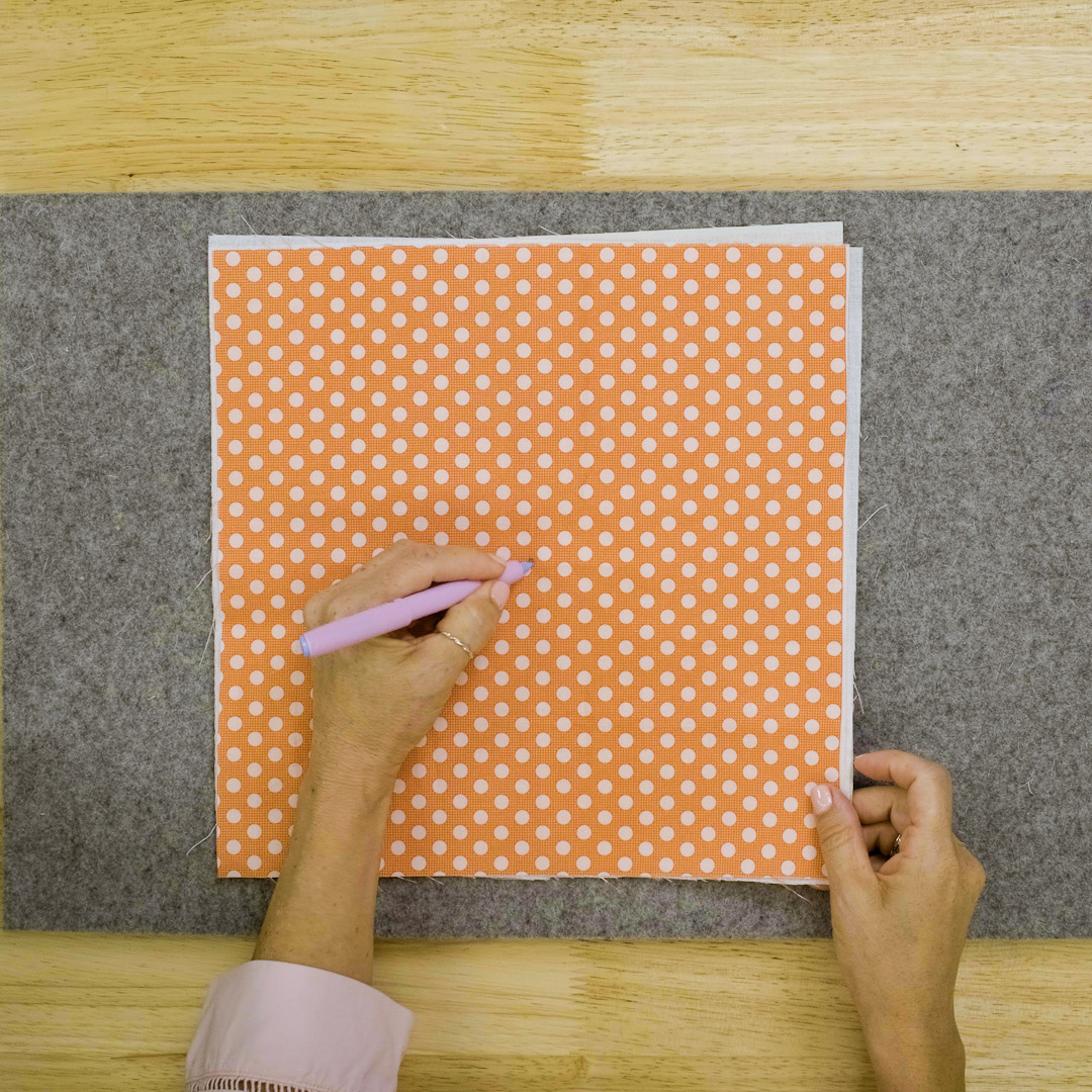 orange polka dot fabric being marked in the center with a purple temporary marker