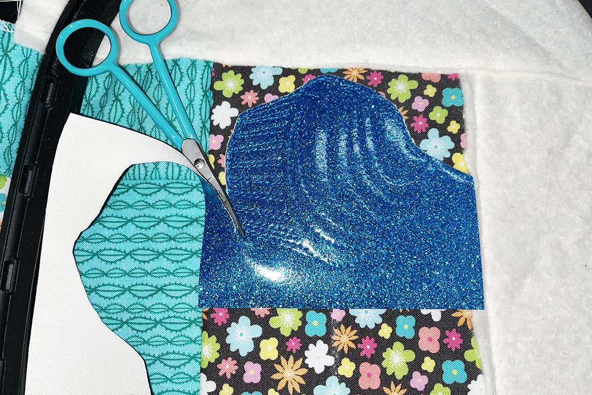 scissors used to trim away excess vinyl around finished embroidery motif