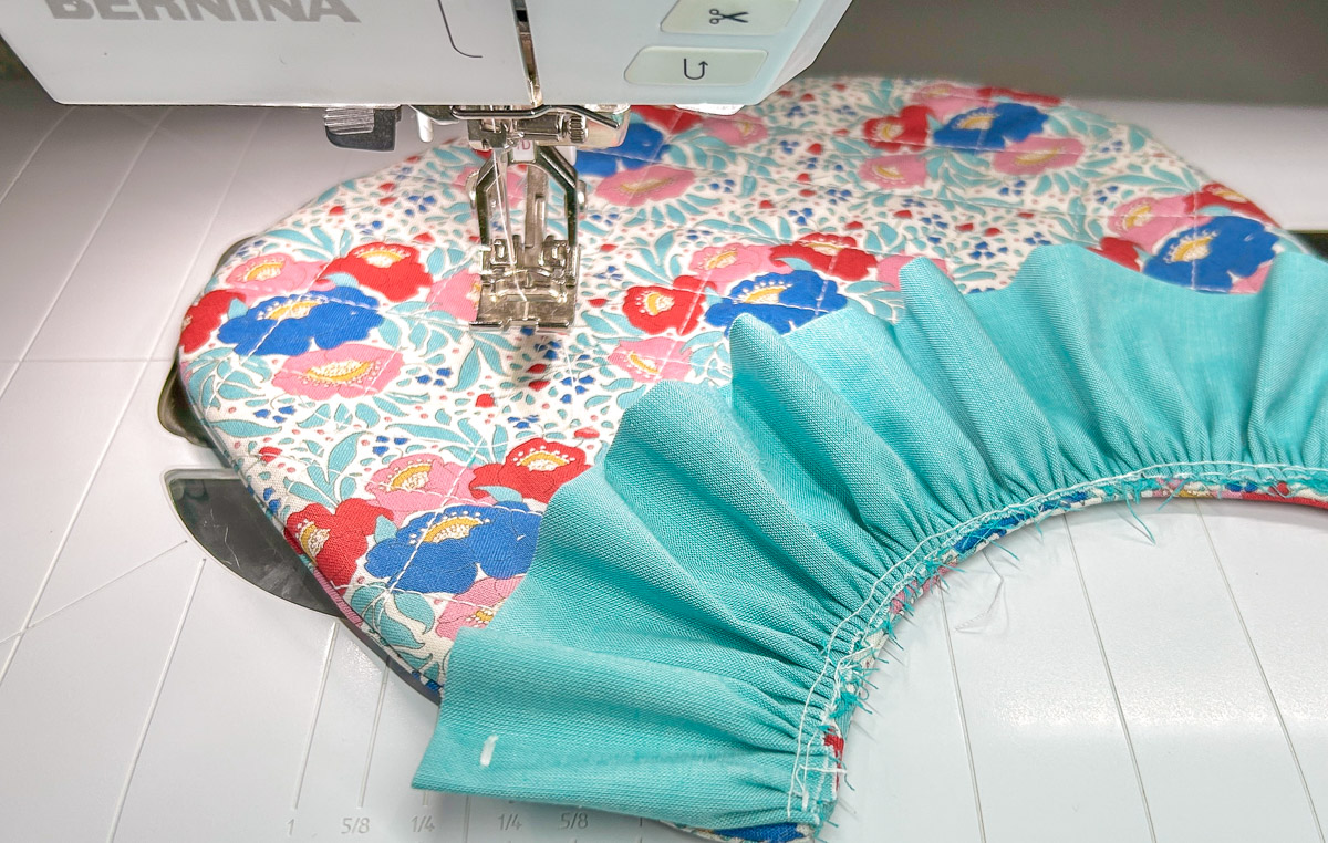 Blue ruffle stitched onto colorful bib with sewing machine