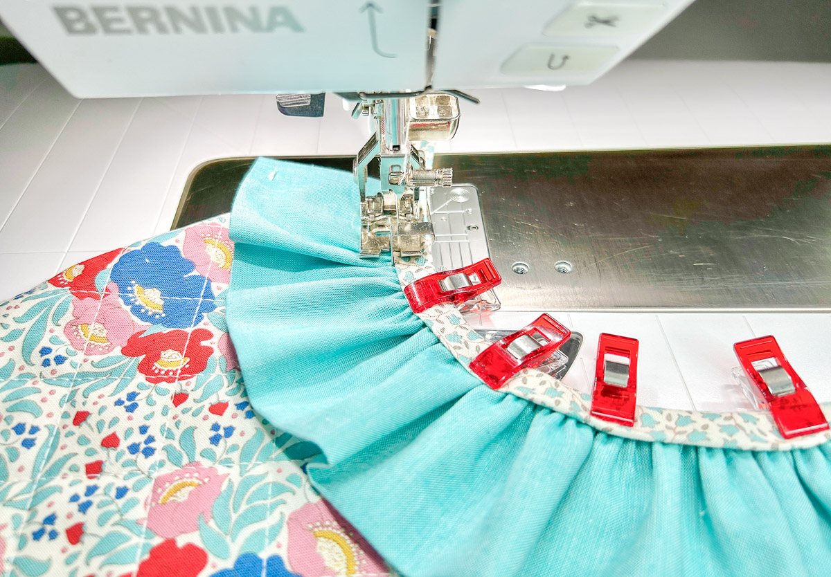 stitching multi-color tie onto blue ruffle
