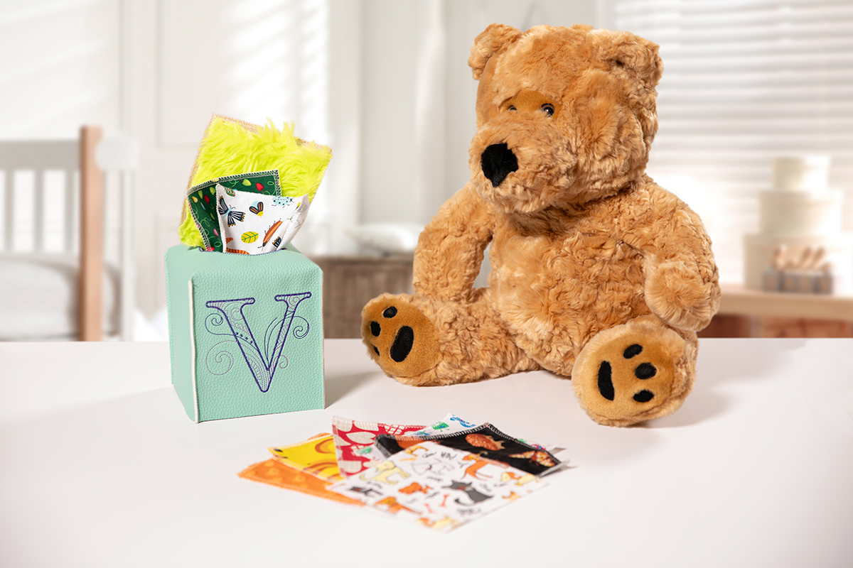 sensory toy box on table next to a brown teddy bear.