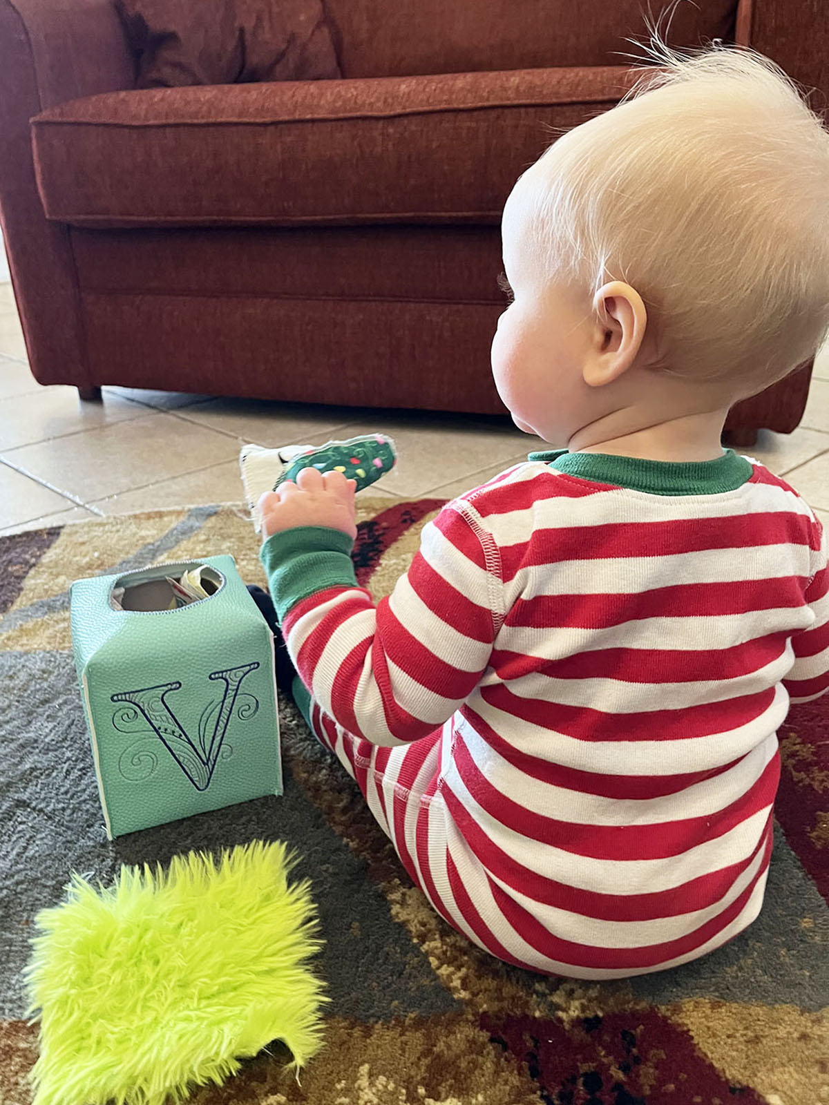 Baby holding green sensory toy in room