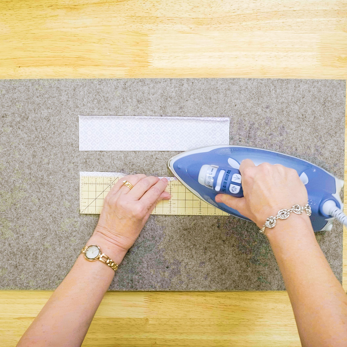 using an iron to press the edges of fabric.