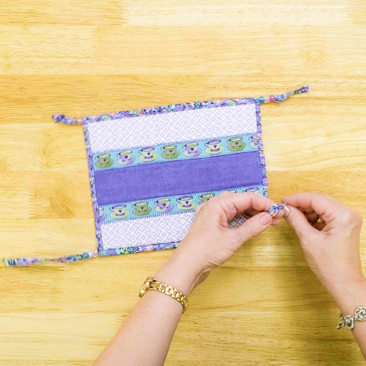 hands ties knots in the binding of the snack mat.