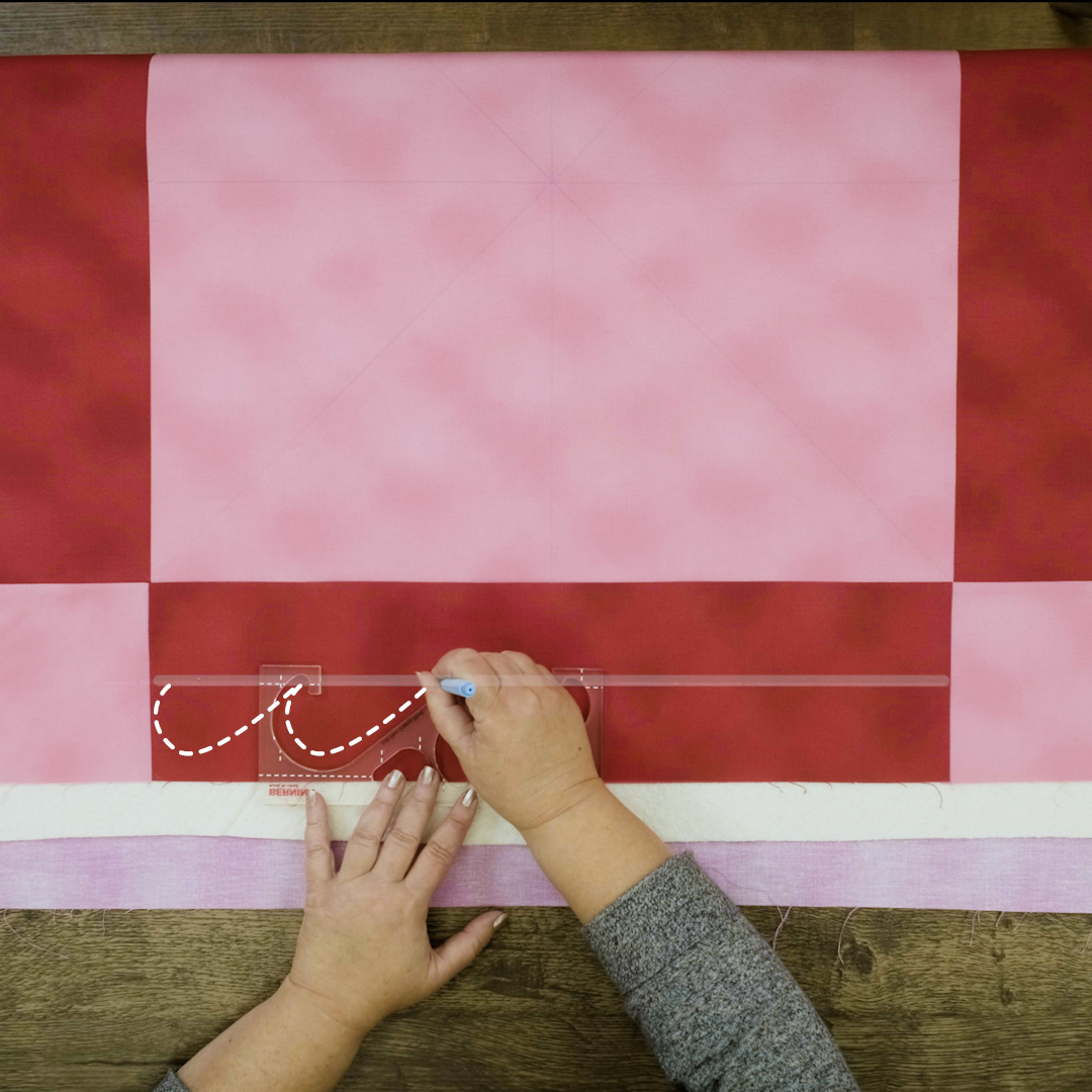 Overhead view of red and pink checkered quilt with ruler guide aligned with stitches