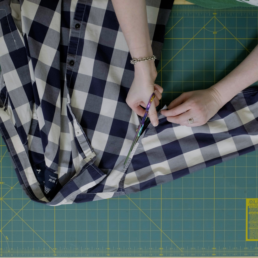 Scissors cutting shirt sleeves along chest seam