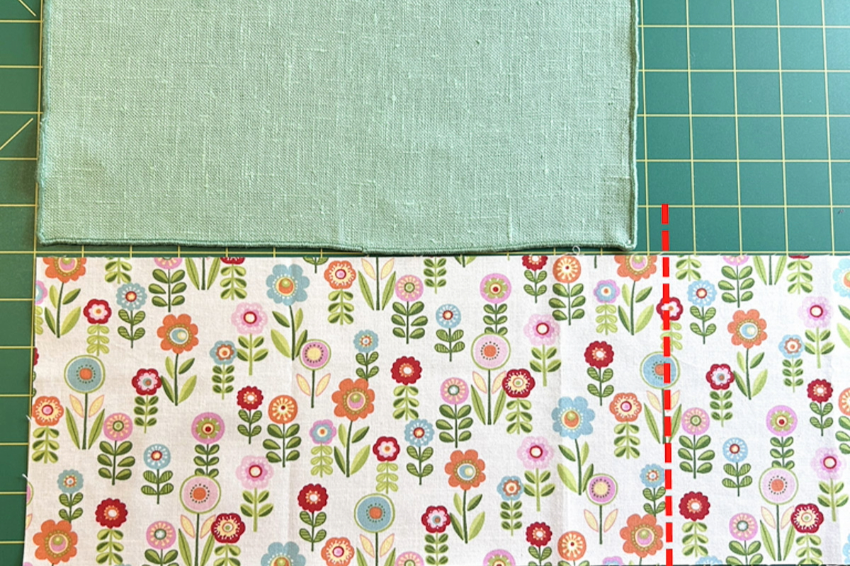 Overhead shot of a plain green napkin being aligned to long edge of flowered napkin