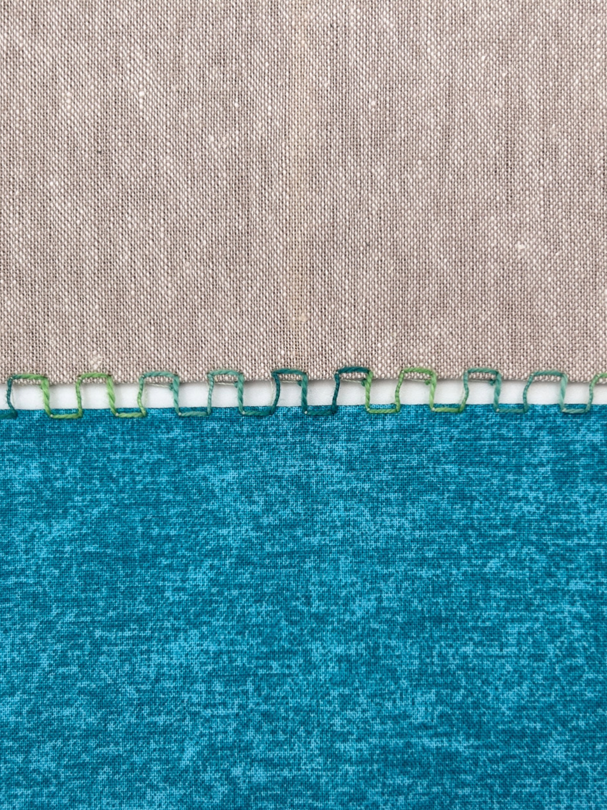 Close-up view of blue and white fabric sewn together in a variegated thick thread.