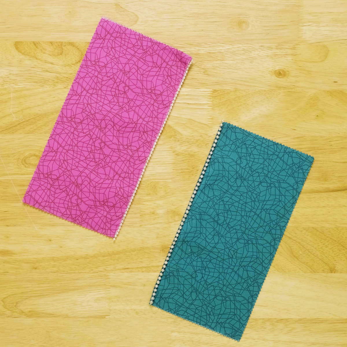 Green and pink fabric strips, with beads, on a light wood background.