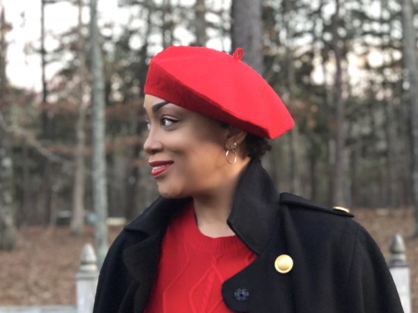 Woman wearing red wool-felt beret while standing in the woods