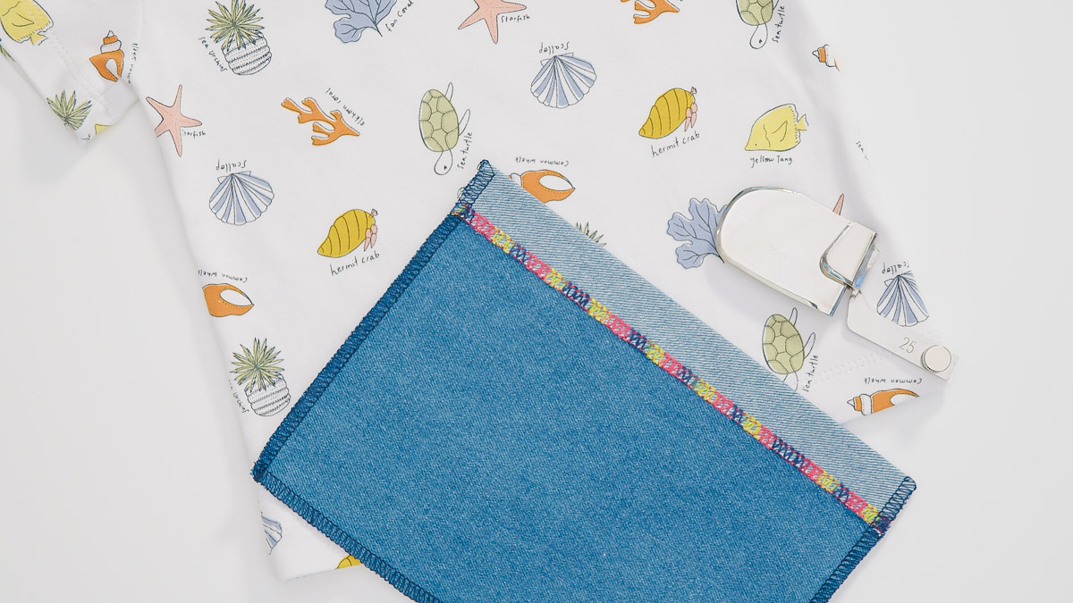 blue fabric and sea-themed white fabric on a white background, featring a variety of colorful threads