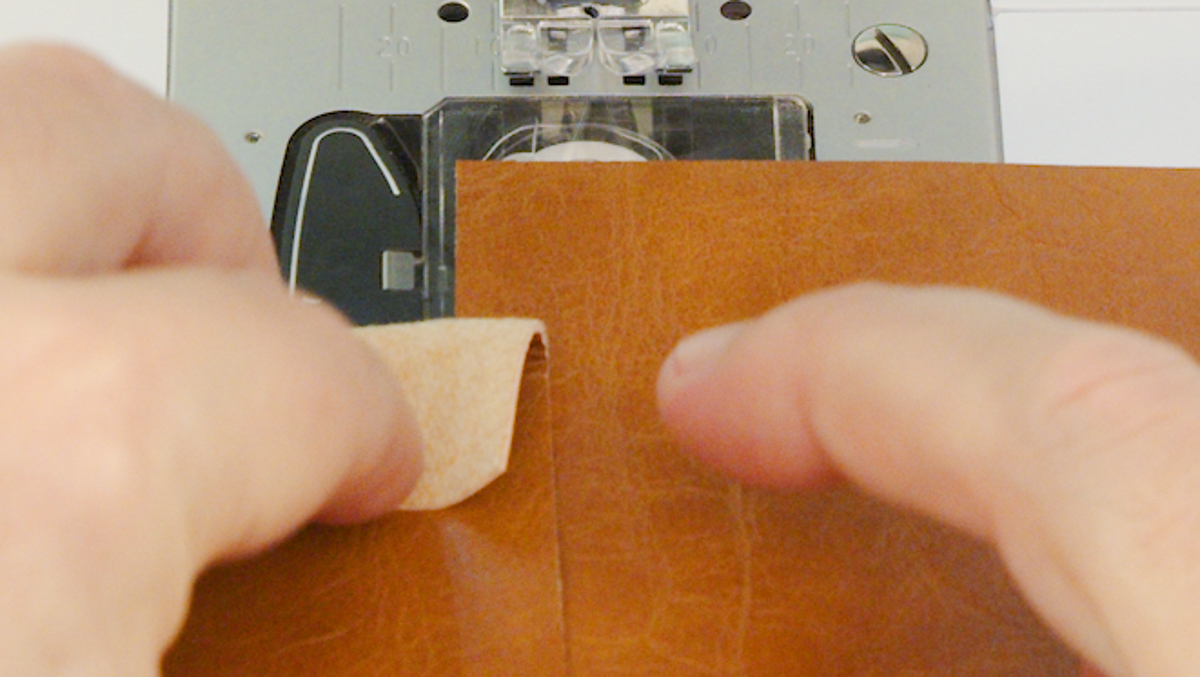 Close up of two leather edges being sewn.