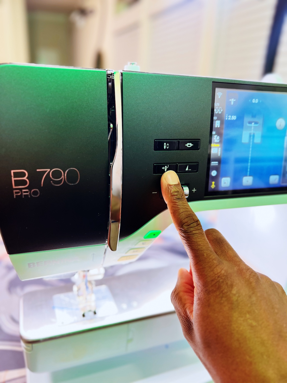 a Black man's finger pressing the BERNINA B 790 PRO buttons