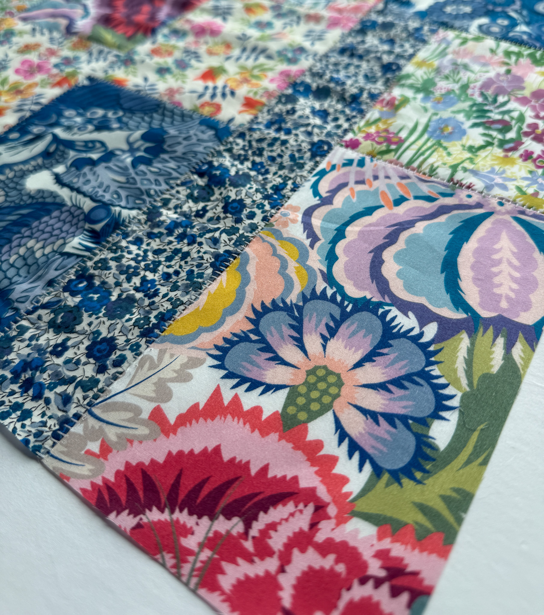 A close-up image of a patchwork made using an overlock stitch and Liberty Tana Lawn