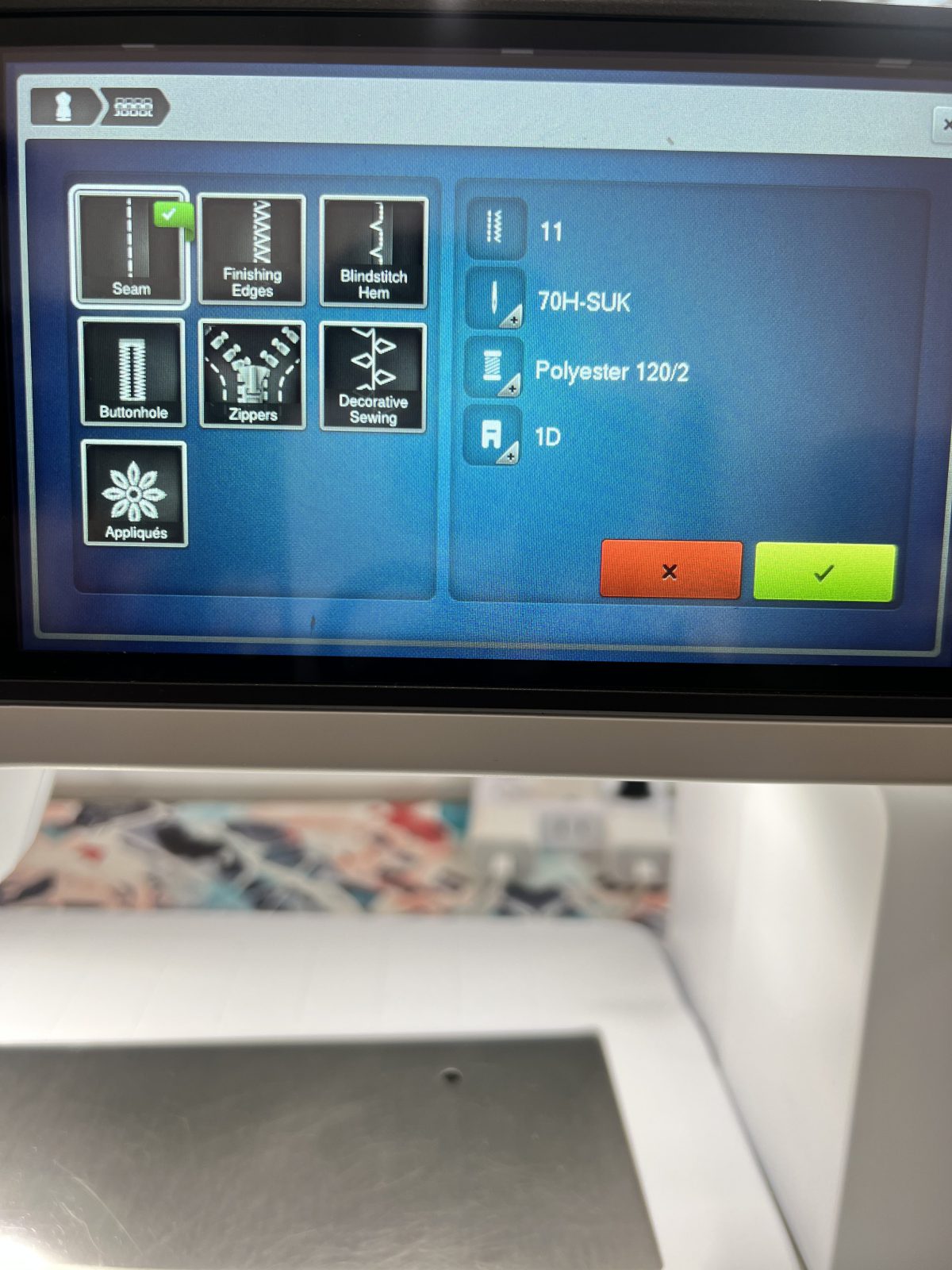 Close-up of a Bernina B 790 Pro sewing machine screen displaying stitch and function options. The screen shows icons for seam, finishing edges, blindstitch hem, buttonhole, zippers, decorative sewing, and appliqués. The right panel lists settings: stitch 11, needle 70H-SUK, thread polyester 120/2, and presser foot 1D, with green check and red X buttons at the bottom.