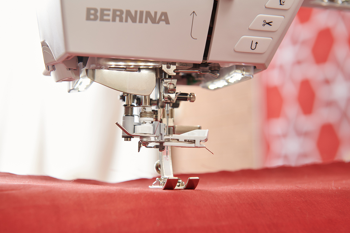 Close up image of sewing machine presser foot and automatic needle threader mechanism.
