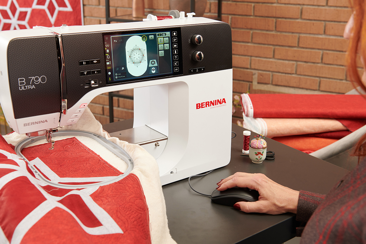 A person sitting in front of a sewing machine with a corded mouse attached.